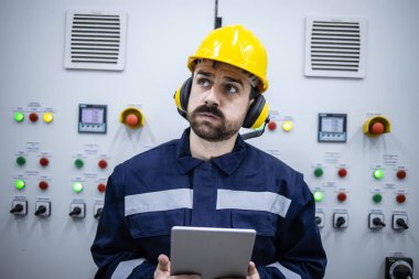 Portrait of worried electrical engineer or serviceman trying to detect and fix the problem in factory.