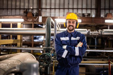 Portrait of petrochemical refinery worker wearing earmuff due to noisy environment in factory.