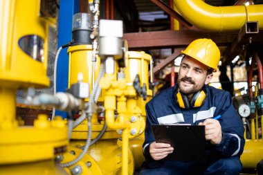 Man controlling natural gas consumption and supply at refinery distribution plant.