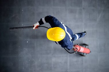 Top view of courageous firefighter running with fire extinguisher to stop disaster.