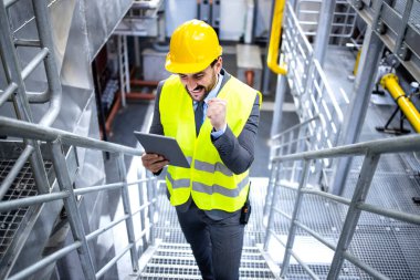 Happy male factory manager using digital tablet in energy power plant.