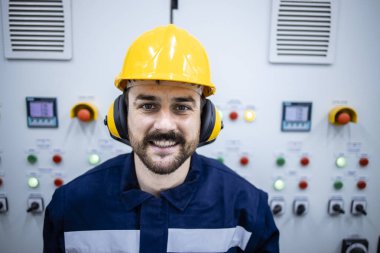 Portrait of smiling bearded worker standing inside factory building.