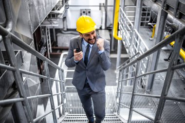 Portrait of successful factory manager in elegant suit walking through power plant.