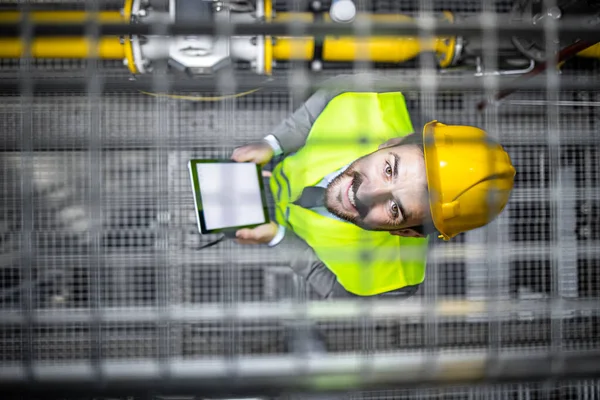 Top view of refinery manager with digital tablet standing in oil production platform.