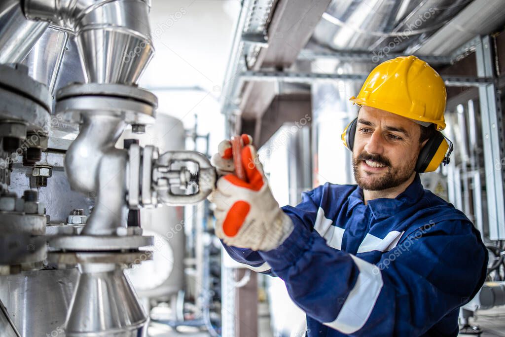 Caucasian smiling man working in heating plant adjusting water pressure and temperature in boiler room.