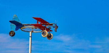 Güneşli bir günde mavi gökyüzüne karşı bisiklet tekerleğinden ev yapımı rüzgar gülü uçak ve renkli tahtalar. arkaplan