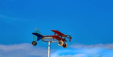 Güneşli bir günde mavi gökyüzüne karşı bisiklet tekerleğinden ev yapımı rüzgar gülü uçak ve renkli tahtalar. arkaplan