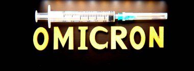 Ahşap harflerden yapılmış omikron kelimesi, siyah arka planda şırınga. Tıbbi konsept - Mutasyona uğramış koronavirüs SARS-CoV-2 grip salgını