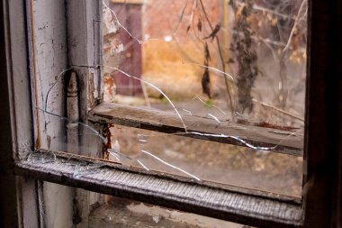 Eski terk edilmiş bir evin camında kırık camlar, evin içinden çekilmiş bir fotoğraf.
