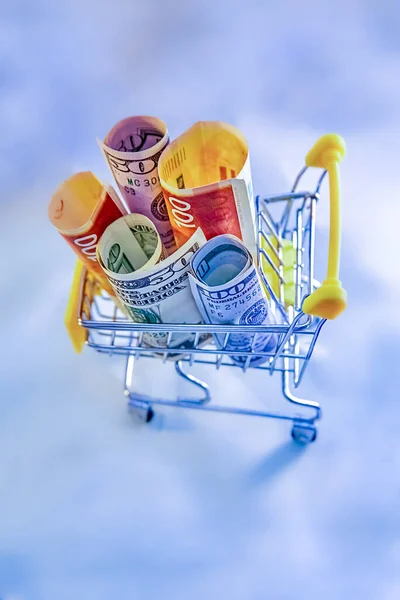 コンセプト 光の背景にお金 ドルとイスラエルの新しいシェルとショッピングカートトロリーズ — ストック写真