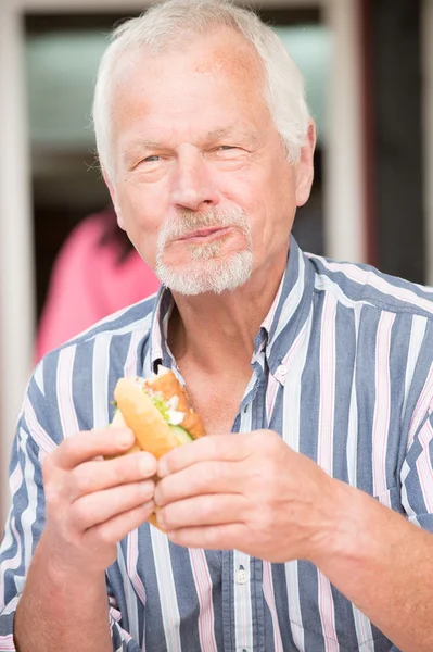 Senior man eating fish — Stockfoto