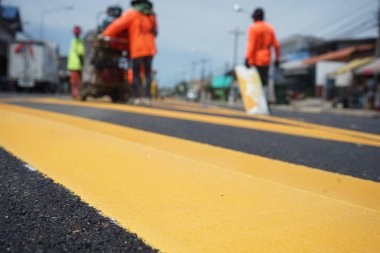 Bulanık görüntü. İşçiler yolun ortasındaki bir adanın kenarını boyuyor..