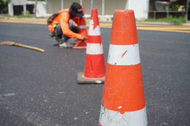 Kırmızı lastik koniler asfalt yola konur. Yoldaki güvenlik için