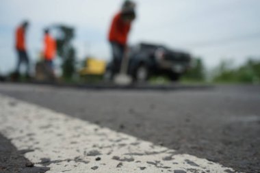 Blurred image of pavement repair work. It's a low angle photo.