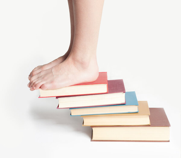 Person standing on a stack of books