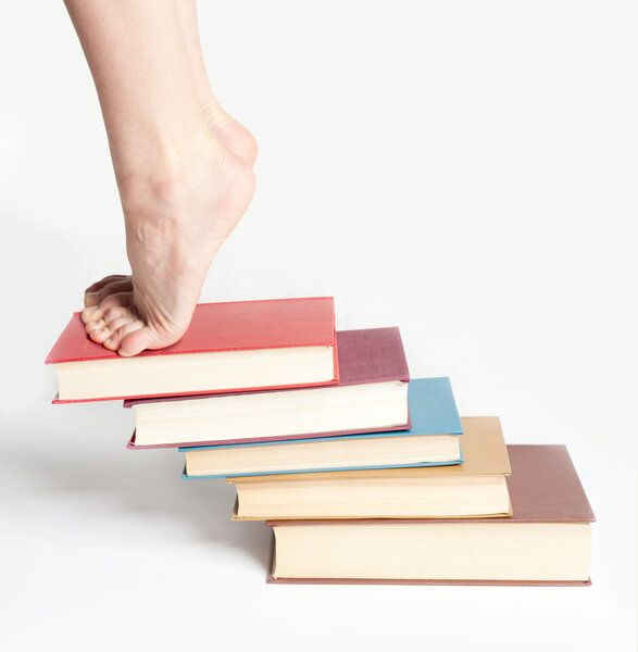 Person standing on a stack of books