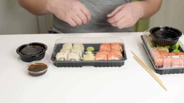 Η έννοια παράδοσης τροφίμων: ο άνθρωπος ανοίγει το παραδοθέν κιβώτιο με το ιαπωνικό φαγητό. Πάρε φαγητό. — Αρχείο Βίντεο