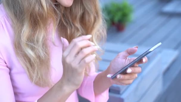 Hübsche junge Frau, die per Telefon SMS schreibt. Glückliche weibliche Person im Café draußen — Stockvideo