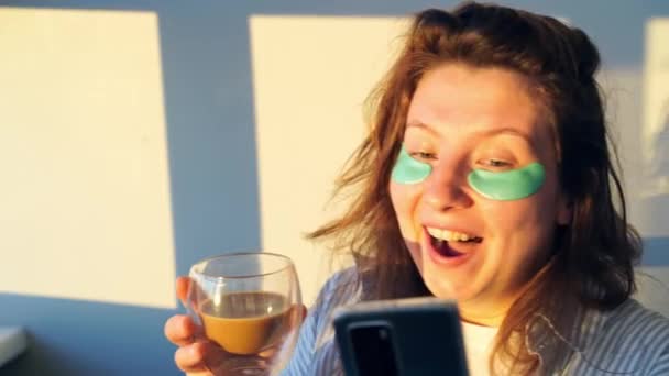 Mladá žena pije kávu doma. Ranní rutina. Páska přes oko pro zdraví kůže — Stock video