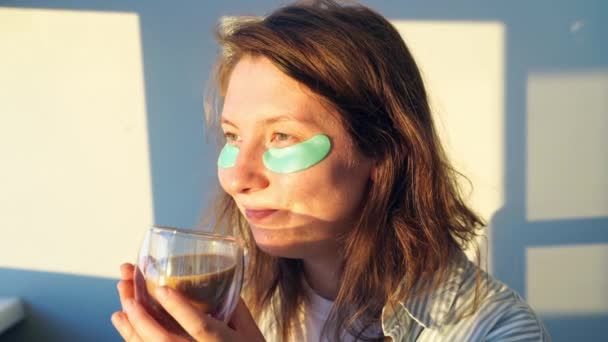 Ung kvinna dricker kaffe hemma. Morgonrutin. Ögonlapp för hudens hälsa — Stockvideo