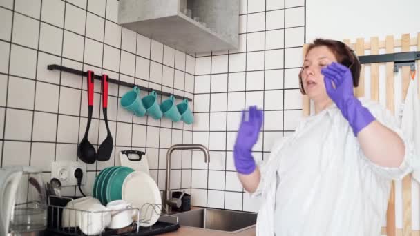 Jonge vrolijke vrouw doet de afwas in de keuken. Helder vrouwelijk portret. Wow emotie — Stockvideo