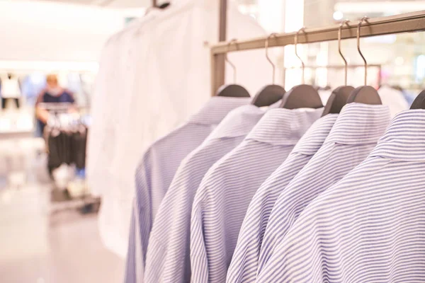 Clothes market interior. Blur light background. Shop shelf. Stock shirts