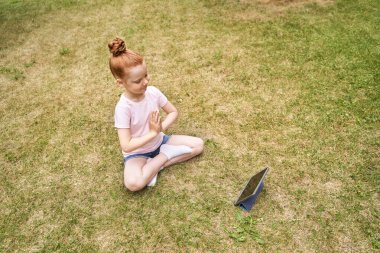 Güzel surat. Kızıl saçlı. Yoga yapan sevimli bir okul çocuğu. Etkin tatil