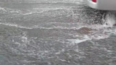 Şehir yağmuru. Büyük su birikintisi. Diğer tarafa bak. Sonbahar tehlikesi. Otomobil ıslak seyahat
