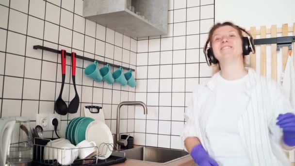 Młoda szczęśliwa kobieta zmywa naczynia w kuchni. Jasny kobiecy portret. Wow emocje — Wideo stockowe