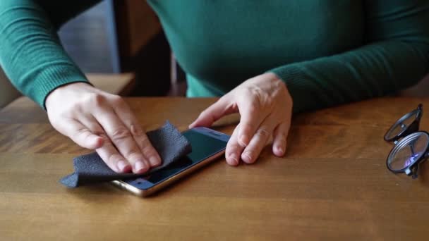 Las manos de mujer limpian el teléfono. Dispositivo limpio con pañuelos de papel negro. Vestido verde — Vídeos de Stock