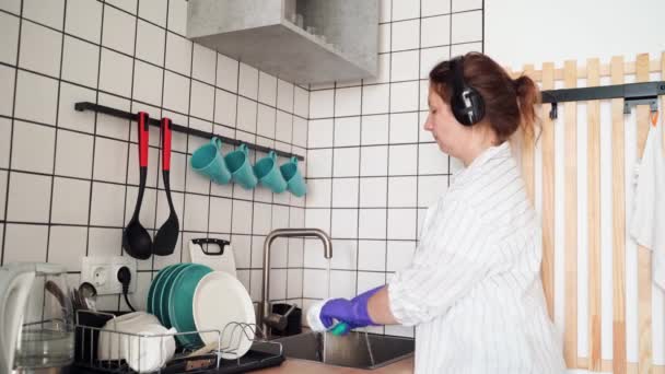 Mujer feliz joven lavar los platos en la cocina. Retrato femenino brillante. Wow emoción — Vídeo de stock