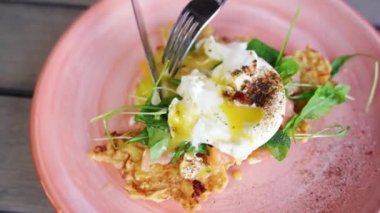 Man eating benedict egg. Cooking potato pancakes. Fork dinner