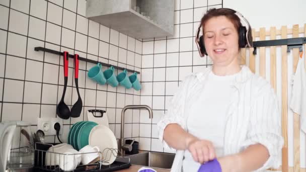 Jovem mulher feliz lavar pratos na cozinha. Retrato feminino brilhante. Uau emoção — Vídeo de Stock