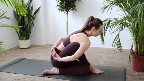 Mujer joven haciendo ejercicio de yoga en casa. Cursos en línea de atención médica. De interior — Vídeos de Stock