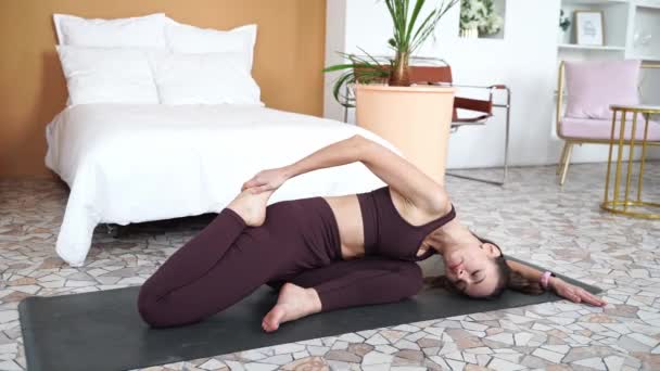 O tânără care face exerciții de yoga acasă. Lecții online de asistență medicală. Interior — Videoclip de stoc