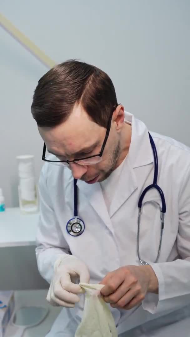 Un medico maschio che mette un guanto medico. Video ritratto di Verticla. Uomo con gli occhiali — Video Stock