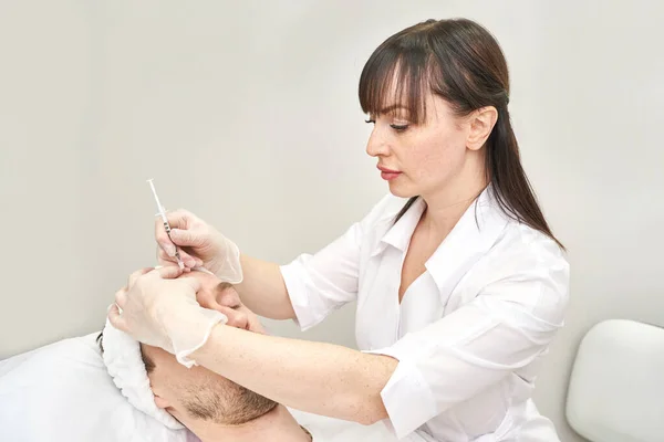 Spritze im Wellness-Salon. Der Arzt legt Handschuhe an. Nahaufnahme. Hübscher männlicher Patient — Stockfoto