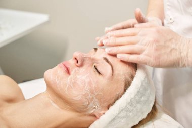 Yüz masajına hazırlanın. Doktor elleri. Güzel bir bayan hasta. Güzellik tedavisi