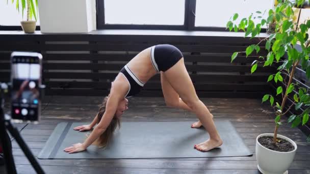 O tânără care face exerciții yoga acasă. Lecții online de asistență medicală. Fitness interior — Videoclip de stoc