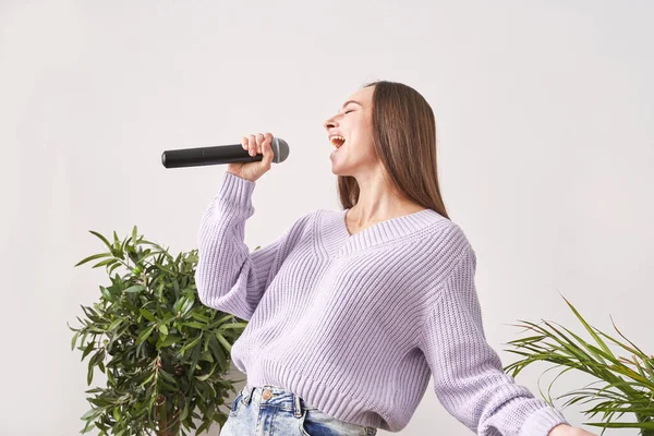 Ung kvinna sjunger hemma. Karaoke svart mikrofon. Hustexter dans. Stockbild