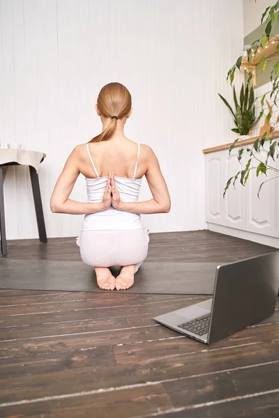 Ung kvinna som tränar yoga hemma. Hälsovård online lektioner. Inomhus Royaltyfria Stockbilder
