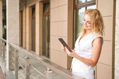 Tabletle mesajlaşan güzel bir genç kadın. Dışarıda mutlu kadınlar var. Yaz