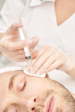 Spa salonunda enjeksiyon. Eldivenli doktor elleri. - Yakın çekim. Güzel erkek hasta.