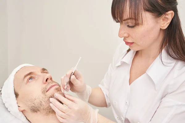 Spritze im Wellness-Salon. Der Arzt legt Handschuhe an. Nahaufnahme. Hübscher männlicher Patient — Stockfoto