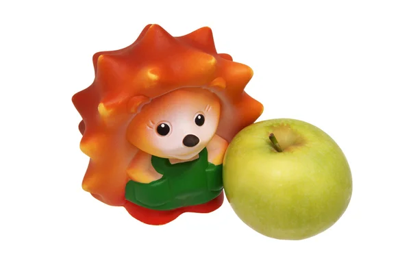 Rubber toy hedgehog and green apple. — Stock Photo, Image