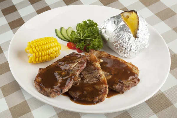 Bone in Lamb with gravy and corn and a baked potato with clipping path — Stock Photo, Image