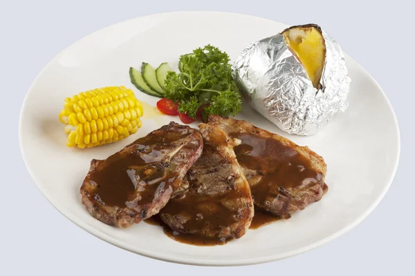 Bone in Lamb with gravy and corn and a baked potato — Stock Photo, Image