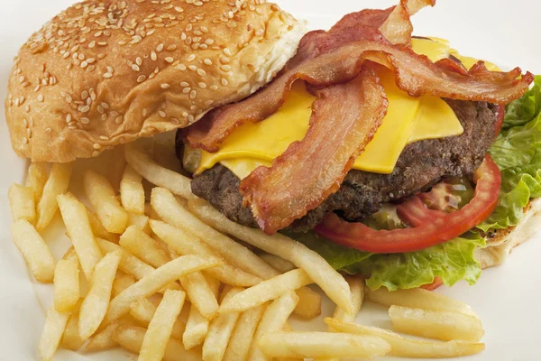 Um delicioso hambúrguer de queijo com bacon e batatas fritas — Fotografia de Stock