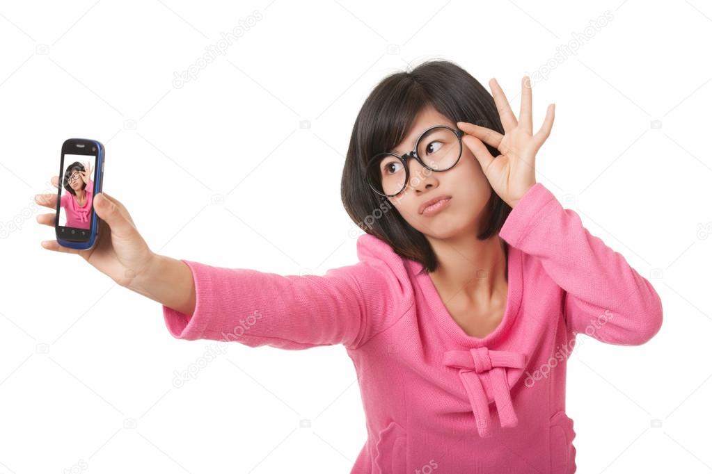 Beautiful Asian woman using a cell phone to take a selfie isolated on a white background