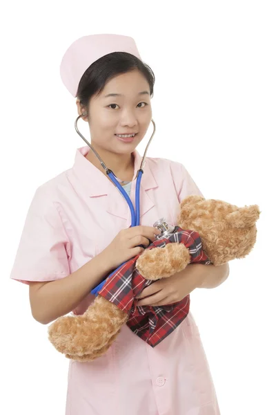 Schöne asiatische Krankenschwester Pflege für einen Teddybär isoliert auf einem weißen Hintergrund — Stockfoto